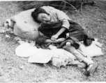 A woman sleeping, possibly cradling a baby: A tired, sick, or weakened refugee during the Chinese civilian evacuation in Liuzhou city, Guangxi province, China, during WWII, in the summer or fall of 1944 as the Japanese swept through as part of the large Ichigo push.