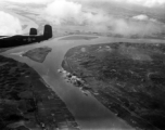 A Mitchell B-25, tail number 444, flies away from a site just bombed in China or Indochina area.