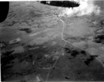 Smoke rises on the ground at a crossroads of the Burma Road after an attack by American B-25s in either SW China, Indochina, or the Burma area.  This might be fairly close to Tengchong in China.