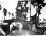 A boat on a canal near a small bridge in rural Yunnan province, China, with American GIs looking on from bridge above. During WWII.