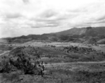 Scenery in China.  Note the young man in work coveralls and holding a carbine in the foreground.  This is probably near Yangkai, Yunnan.