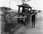 GI rides a sedan chair carried on bamboo poles by two Chinese men. During WWII.