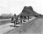 Men carrying gourds in Guilin, near the American air base, with karst mountains and B-25 bombers in the background. During WWII.  From the collection of Hal Geer.