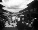 Local scenes and local people in Yunnan province, China, most likely around the Luliang air base area.  A local street in a village or town near the American air base. The sign on the building on the right advertises a tea house 天天有茶社.