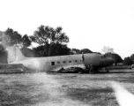 A man in pith hat stands of fuselage remains of a C-47 transport next to railroad track. In the CBI during WWII.