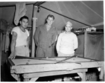 Engineers of the 797th Engineer Forestry Company pose while playing at a miniature pool table in their tent in Burma.  During WWII.