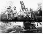 Engineers of the 797th Engineer Forestry Company pose on a log hoisted into the air by a tracked loader.  During WWII.