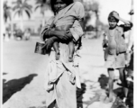 Begging woman holds child on road in town in Burma or India.  Near the 797th Engineer Forestry Company.  During WWII.