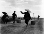 People carrying shoulder poles in China during WWII.