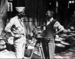 An American photographer (left) talks to a civilian, probably also a photographer (right), at a market in a village in Yunnan province.