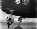 An American aircrew member observes the masking for three new mission symbols on the side of a B-25C at an airbase China. The "Mr. Jiggs" insigne of the 11th Bomb Squadron is visible, as well the previous sixty-three mission symbols.  