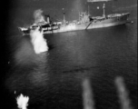 Photo from a B-25 Mitchell running right over a Japanese ship very low during a raid on Hong Kong. Notice bombs in the air on the left, and blurred outline of the plane's twin machine guns in the foreground (presumably this photo is through the tail gunner's window). The separate B-25 that is dropping those bombs is outlined in shadow on the water at the end of the guns.  From a mission on Hong Kong, 491st Bomb Squadron.