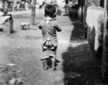 Local people in China: A young child with split pants in a street in China, during WWII.