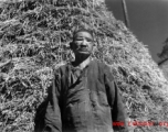 A blind villager in China poses for photographer with a stack of rice straw behind. During WWII.