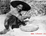 Local people in China: A farmer picks through grain to clean it.