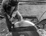 A craftsman repairing a wooden wheel in WWII China. 