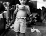 A young boy eats a meal on a boat in China during WWII, probably in Guangxi province, likely Liuzhou or Guilin.