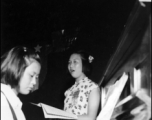 During WWII, as part of an appreciation activity for the American Army Air Force, a Chinese school girl sings while another plays piano.