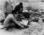 During a short rest period from the construction of an airfield (maybe at Chengdu), Chinese laborers look at "Life" magazine held by Lt. Otto of Troy, New York, in China during WWII.