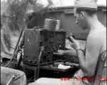 A GI operates a portable radio from the back of a vehicle in the CBI during WWII.