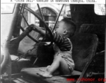 A Chinese toddler playing on a the driver's seat of a jeep in downtown Chengdu, China, during WWII.