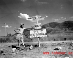 GI leans against sign at junction of Ledo Road and the Burma Road, during WWII.