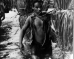 A worker has chopped elephant grand and bamboo, then carries the huge load through a stream to build bashas (huts) for allies, Kachin Rangers.  Photo from Jim Fletcher.