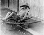 Farming in China: Farmer resting on wheelbarrow.