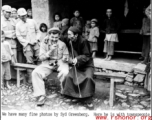 Photographer and funny man Syd Greenberg tries out a long pipe with a local Chinese gentleman, and soldiers and kids look on with enthusiasm, before the Salween River campaign. 