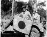 Ival Baker shows souvenir captured Japanese flag, while his bodyguard watches on. During WWII, in China.  Photo from Ival Baker.