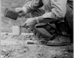 Member of the 988th Signal Service Battalion grabs a bite to eat along the Burma Road. "We quickly learned to heat cans of food on the engine, and have it warm and ready for a quick stop."