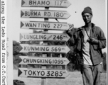 An American GI poses next to a heavily loaded sign post along the Ledo Road during WWII.  Photo from C. C. Carter.