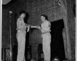 A GI wins a prize during a variety show, while the band Jive-o-Lieps waits to play music in the CBI during WWII. 54th Air Service Group.  Photo from Cal West.