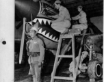 A Curtiss P-40 is being serviced by Sgts. Bloom, Dull, Yaranow, and Baker, while a Chinese soldier stands guard.