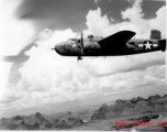 B-25 Mitchell bomber surges forward in flight over limestone karst mountains, in the area of southern China, Indochina, or Burma.