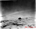 A mountain pokes through the clouds during a war time flight of US planes.