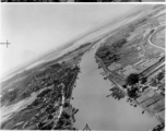 A fly-by of a rural area with a bombed bridge in the background, probably in SW China, Indochina, or the China-Burma border region.  