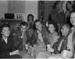 Celebrities visit and perform at Yangkai, Yunnan province, during WWII: GIs and medical staff share a meal with celebrities, including Betty Yeaton seated, Jinx Falkenburg standing in right background, and a Hollywood movie star on far left, and Mary Landa seated against back wall.