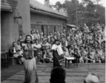 Celebrities (including here Mary Landa dancing, and apparently Ruth Dennis playing instrument) perform on an outdoor stage set up at the "Last Resort" at Yangkai, Yunnan province, during WWII. Notice both Americans and Chinese in the audience for this USO event.