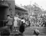 Celebrities (including Ann Sheridan, Ben Blue, and and Ruth Dennis playing an instrument in this shot) perform on an outdoor stage set up at the "Last Resort" at Yangkai, Yunnan province, during WWII. Notice both Americans and Chinese in the audience for this USO event.