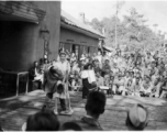 Celebrities (including Ann Sheridan hamming it up with Ben Blue, and Ruth Dennis playing an instrument in this shot) perform on an outdoor stage set up at the "Last Resort" at Yangkai, Yunnan province, during WWII. Notice both Americans and Chinese in the audience for this USO event.