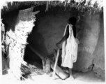 A woman uses a "dhenki" foot lever for dehusking grain. India.  Scenes in India witnessed by American GIs during WWII. For many Americans of that era, with their limited experience traveling, the everyday sights and sounds overseas were new, intriguing, and photo worthy.